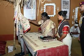 राष्ट्रपति द्रौपदी मुर्मु जनजातीय कलाकारों द्वारा बनाई गई पेंटिंग और हस्तशिल्प का अवलोकन करते हुए।