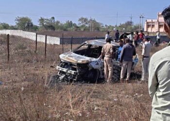 यह तस्वीर एक सुनसान सड़क पर खड़ी जली हुई कार और उसके चारों ओर लगी पुलिस की 'येलो टेप' (Crime Scene) को दर्शाती है, जो मामले की गंभीरता और रहस्य को उजागर करती है।