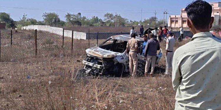 यह तस्वीर एक सुनसान सड़क पर खड़ी जली हुई कार और उसके चारों ओर लगी पुलिस की 'येलो टेप' (Crime Scene) को दर्शाती है, जो मामले की गंभीरता और रहस्य को उजागर करती है।