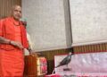 अयोध्या के राम मंदिर ट्रस्ट कार्यालय में कड़े सुरक्षा घेरे के बीच मेज पर सजी सोने की रामचरितमानस, स्वर्ण हार और चरण पादुकाओं को दिखाते ट्रस्ट के पदाधिकारी।