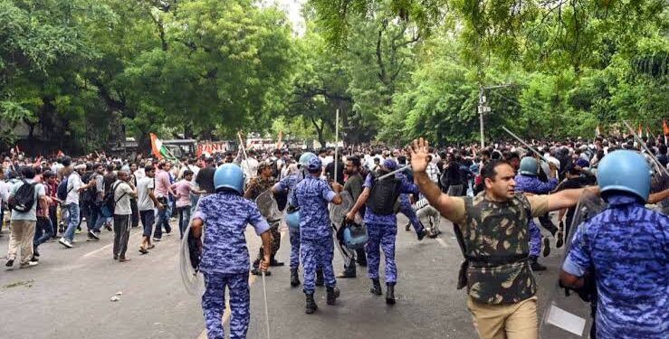 नई दिल्ली में संसद मार्ग के पास पुलिस बैरिकेडिंग और सुरक्षा में तैनात जवानों के साथ गृह मंत्रालय (MHA) के लोगो की प्रतीकात्मक तस्वीर।
