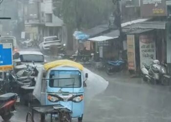 मूसलाधार बारिश में छाता लेकर सड़क पार करते लोग और बादलों की तेज गड़गड़ाहट व आकाशीय बिजली चमकने की प्रतीकात्मक संयुक्त तस्वीर।