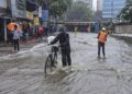 भारी मानसूनी बादलों से घिरा भोपाल का बड़ा तालाब और सड़क पर मूसलाधार बारिश के बीच छाता लेकर चलते राहगीरों की प्रतीकात्मक तस्वीर।