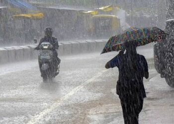 मध्य प्रदेश के राजमार्ग पर मूसलाधार बारिश के बीच हेडलाइट जलाकर रेंगते हुए वाहन और आसमान में कड़कती आकाशीय बिजली की प्रतीकात्मक तस्वीर।