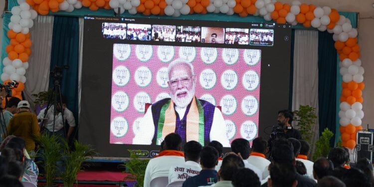 हरदा की माहेश्वरी धर्मशाला में स्क्रीन के माध्यम से सेवा संकल्प बाइक राइडर्स से वर्चुअल संवाद करते प्रधानमंत्री नरेंद्र मोदी और मंच पर उपस्थित भाजपा प्रदेश अध्यक्ष हेमंत खण्डेलवाल व अन्य नेतागण।